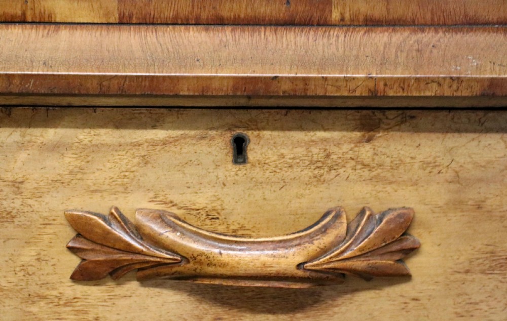 A Victorian light wood chest of drawers with two short drawers over three long drawers, featuring carved leaf handles and a solid plinth base. View X