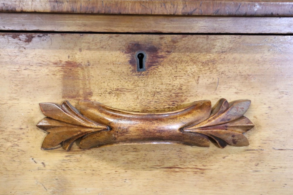 A Victorian light wood chest of drawers with two short drawers over three long drawers, featuring carved leaf handles and a solid plinth base. View XI