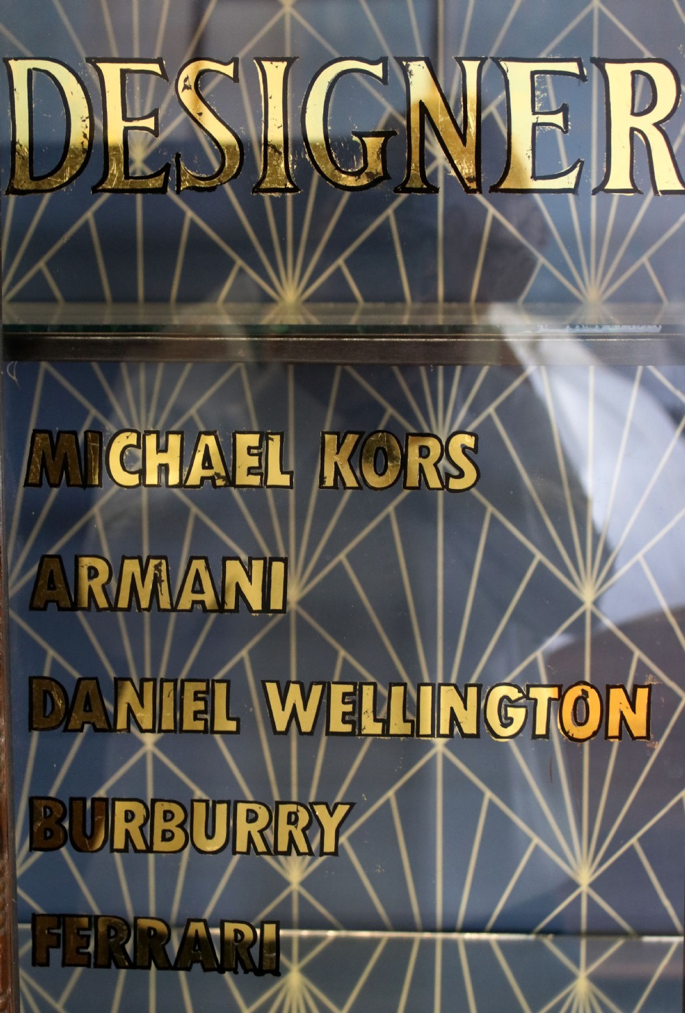 A tall mahogany glazed display cabinet featuring two central glass doors, glazed sides, turned legs, a lower undertier shelf, and gilded gold lettering inside. View VIII