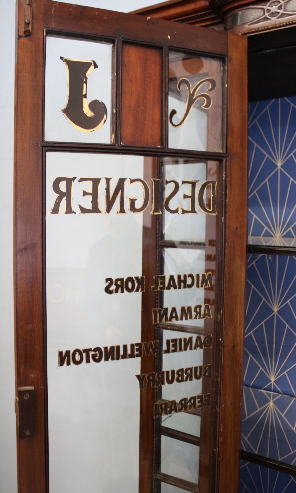 A tall mahogany glazed display cabinet featuring two central glass doors, glazed sides, turned legs, a lower undertier shelf, and gilded gold lettering inside. View XII