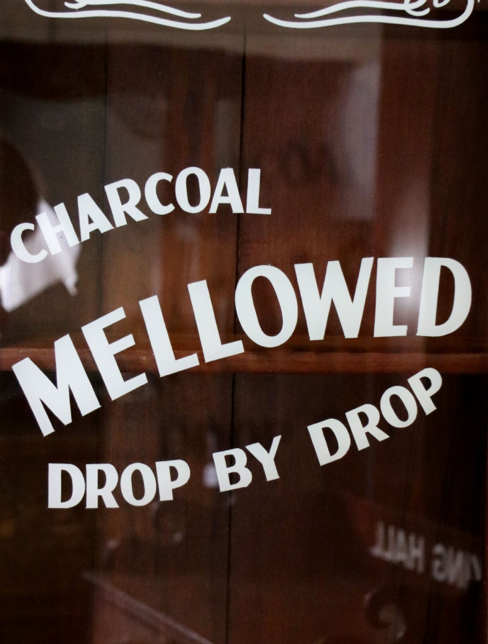 A late Victorian warm brown wooden cabinet featuring a glazed upper display section with white Jack Daniels typography and two lower panelled doors. View XIII