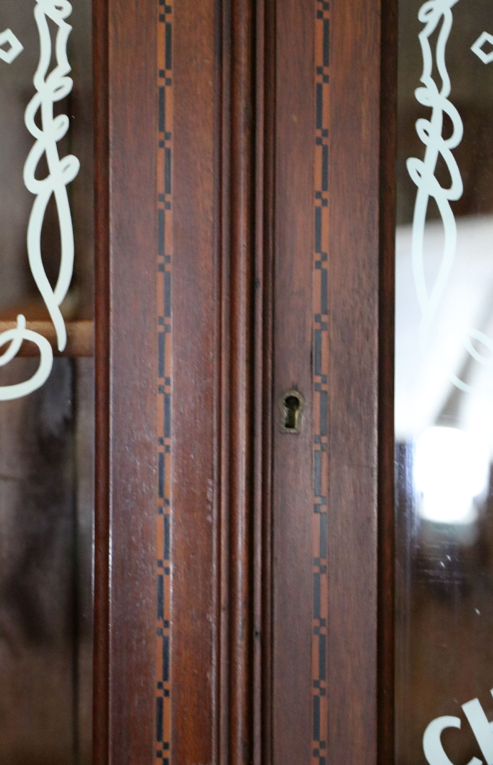 A late Victorian warm brown wooden cabinet featuring a glazed upper display section with white Jack Daniels typography and two lower panelled doors. View XVI