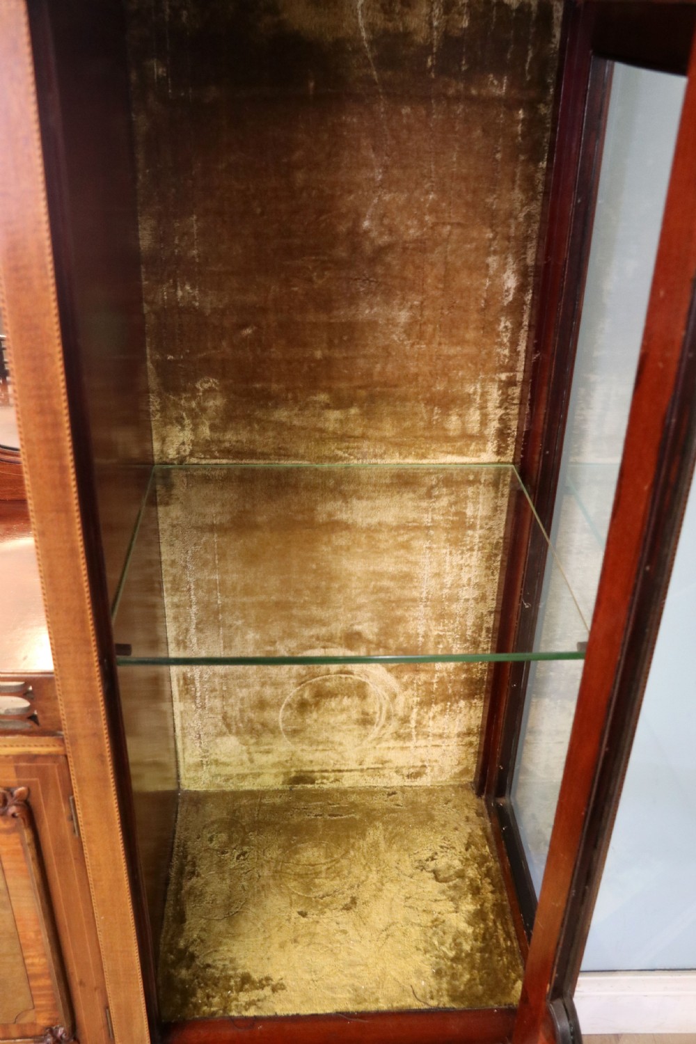 A late 19th-century mahogany display cabinet featuring a drop-centre mirror back, detailed floral marquetry inlays, glazed side doors, and a lower open shelf. View XIV
