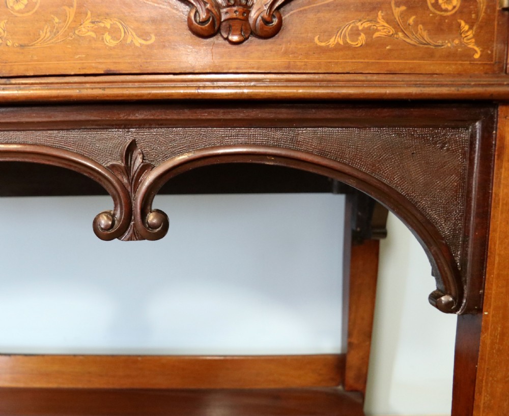 A late 19th-century mahogany display cabinet featuring a drop-centre mirror back, detailed floral marquetry inlays, glazed side doors, and a lower open shelf. View XIX