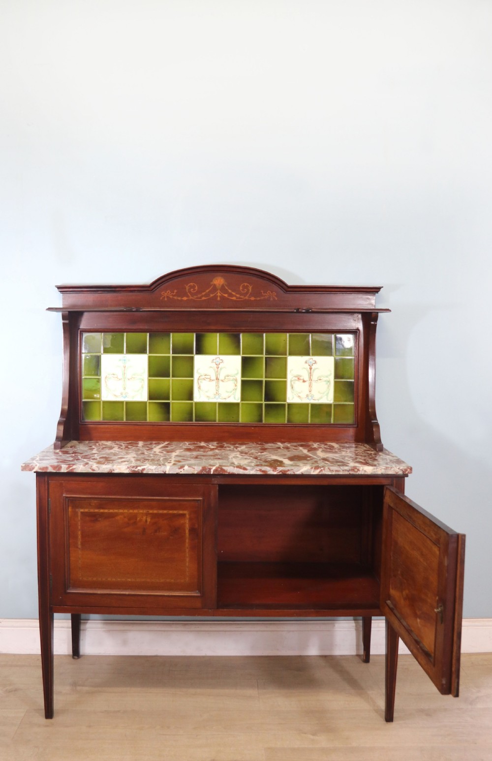 An Edwardian mahogany washstand featuring a red variegated marble top, a splashback set with green ceramic tiles, inlaid cupboard doors, and tapered legs. View III