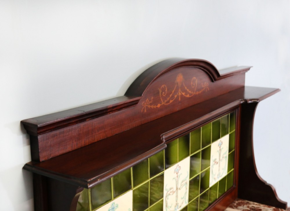 An Edwardian mahogany washstand featuring a red variegated marble top, a splashback set with green ceramic tiles, inlaid cupboard doors, and tapered legs. View VII
