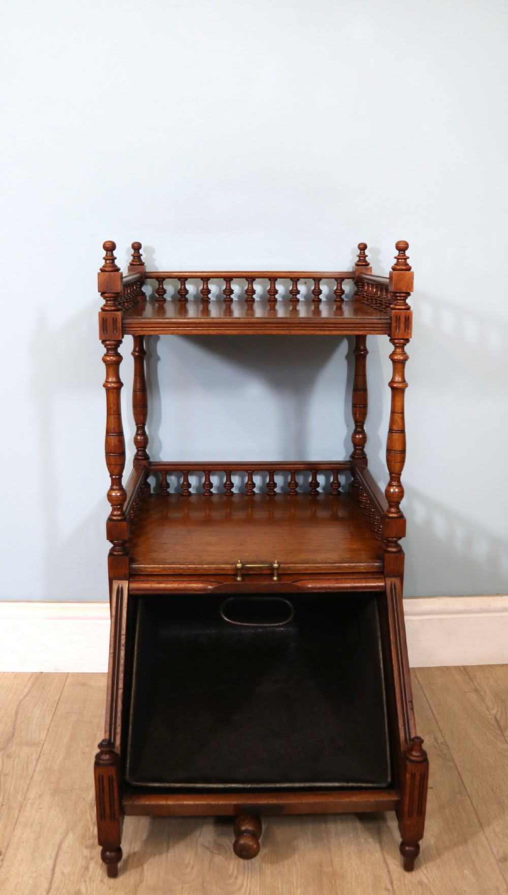 A Victorian Gothic Revival solid walnut coal purdonium featuring a carved drop-front compartment, turned spindle galleries, and upper open shelves. View IV