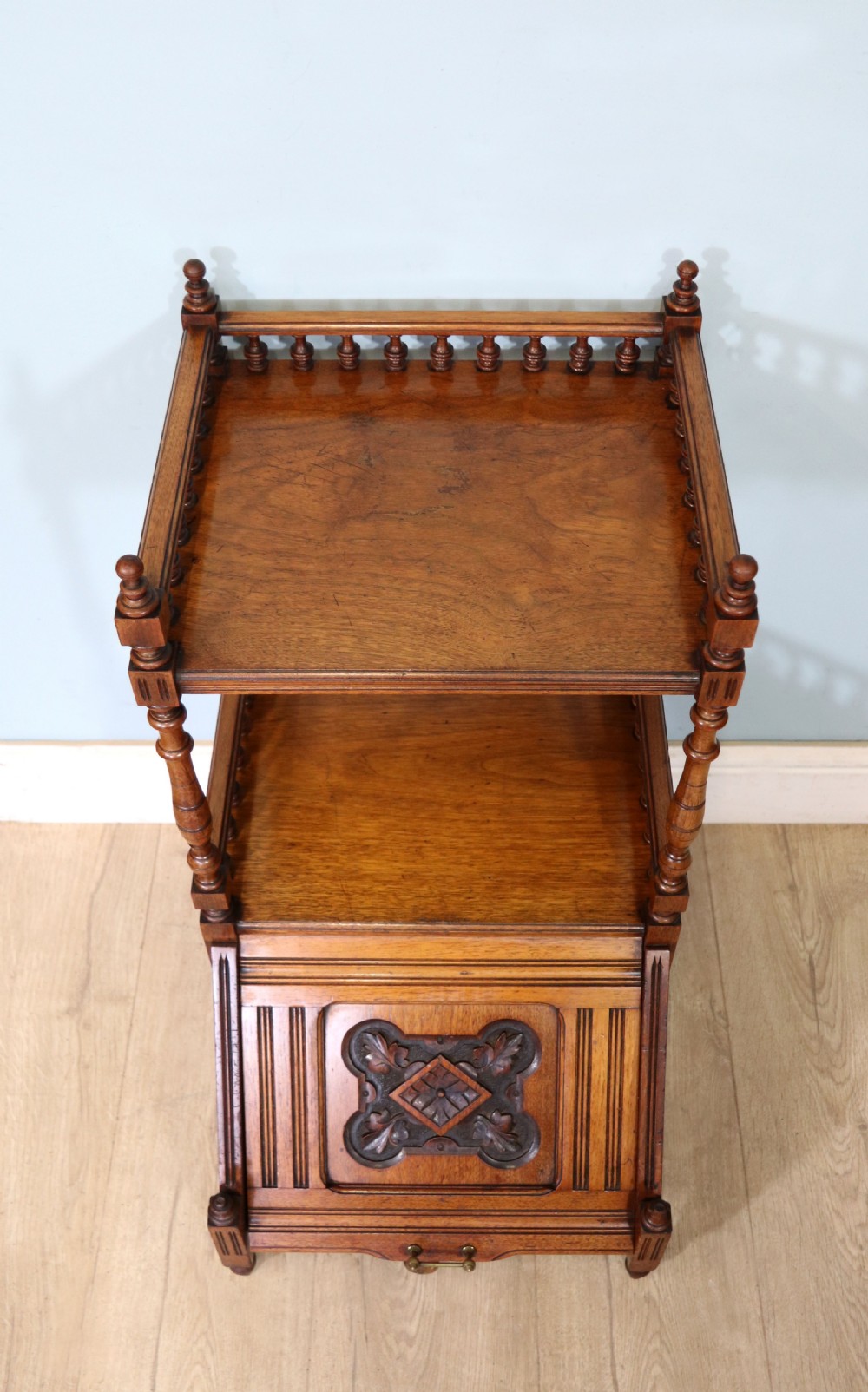 A Victorian Gothic Revival solid walnut coal purdonium featuring a carved drop-front compartment, turned spindle galleries, and upper open shelves. View V