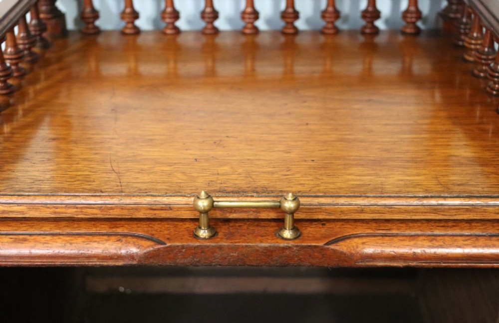 A Victorian Gothic Revival solid walnut coal purdonium featuring a carved drop-front compartment, turned spindle galleries, and upper open shelves. View IX