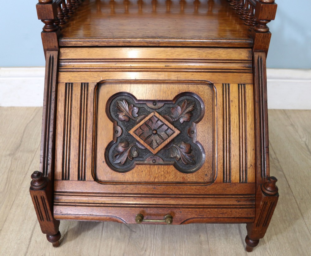 A Victorian Gothic Revival solid walnut coal purdonium featuring a carved drop-front compartment, turned spindle galleries, and upper open shelves. View XI
