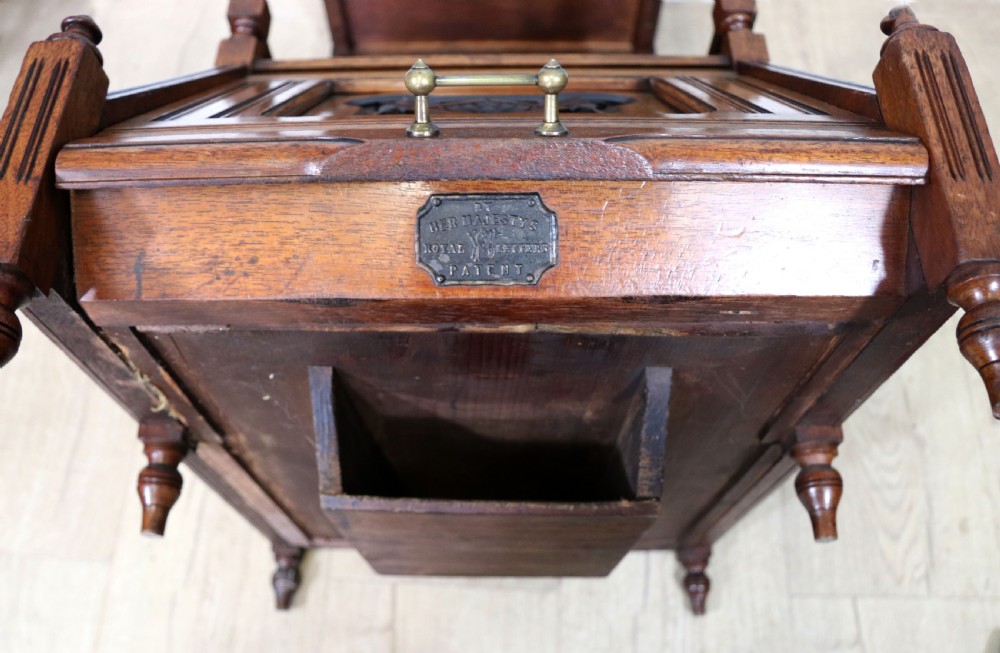 A Victorian Gothic Revival solid walnut coal purdonium featuring a carved drop-front compartment, turned spindle galleries, and upper open shelves. View XIX