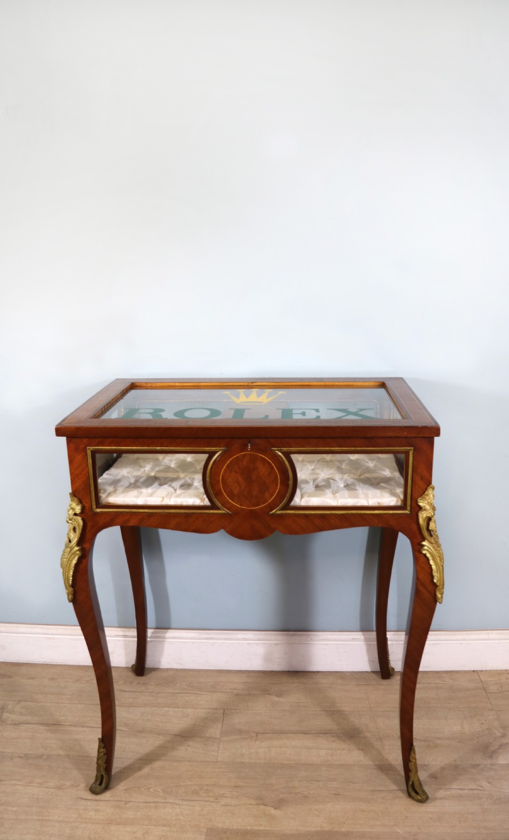A mahogany and kingwood veneered bijouterie display table featuring glazed panels, cabriole legs with brass mounts, and a buttoned cream interior. View II