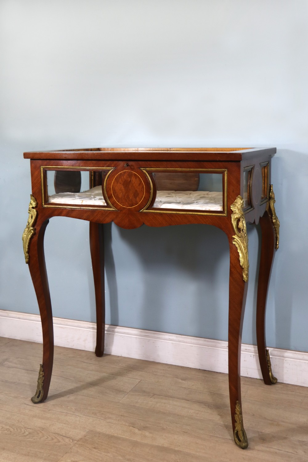 A mahogany and kingwood veneered bijouterie display table featuring glazed panels, cabriole legs with brass mounts, and a buttoned cream interior. View III