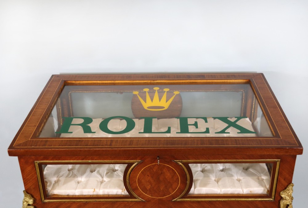 A mahogany and kingwood veneered bijouterie display table featuring glazed panels, cabriole legs with brass mounts, and a buttoned cream interior. View IV