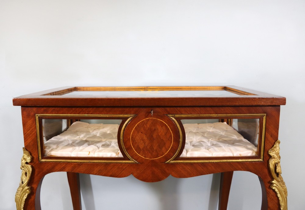 A mahogany and kingwood veneered bijouterie display table featuring glazed panels, cabriole legs with brass mounts, and a buttoned cream interior. View V