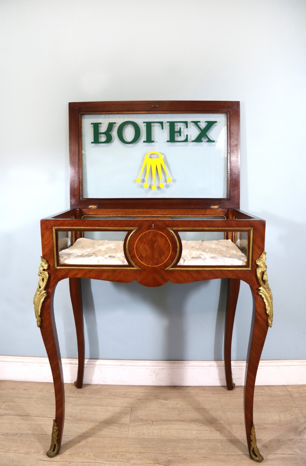 A mahogany and kingwood veneered bijouterie display table featuring glazed panels, cabriole legs with brass mounts, and a buttoned cream interior. View VI