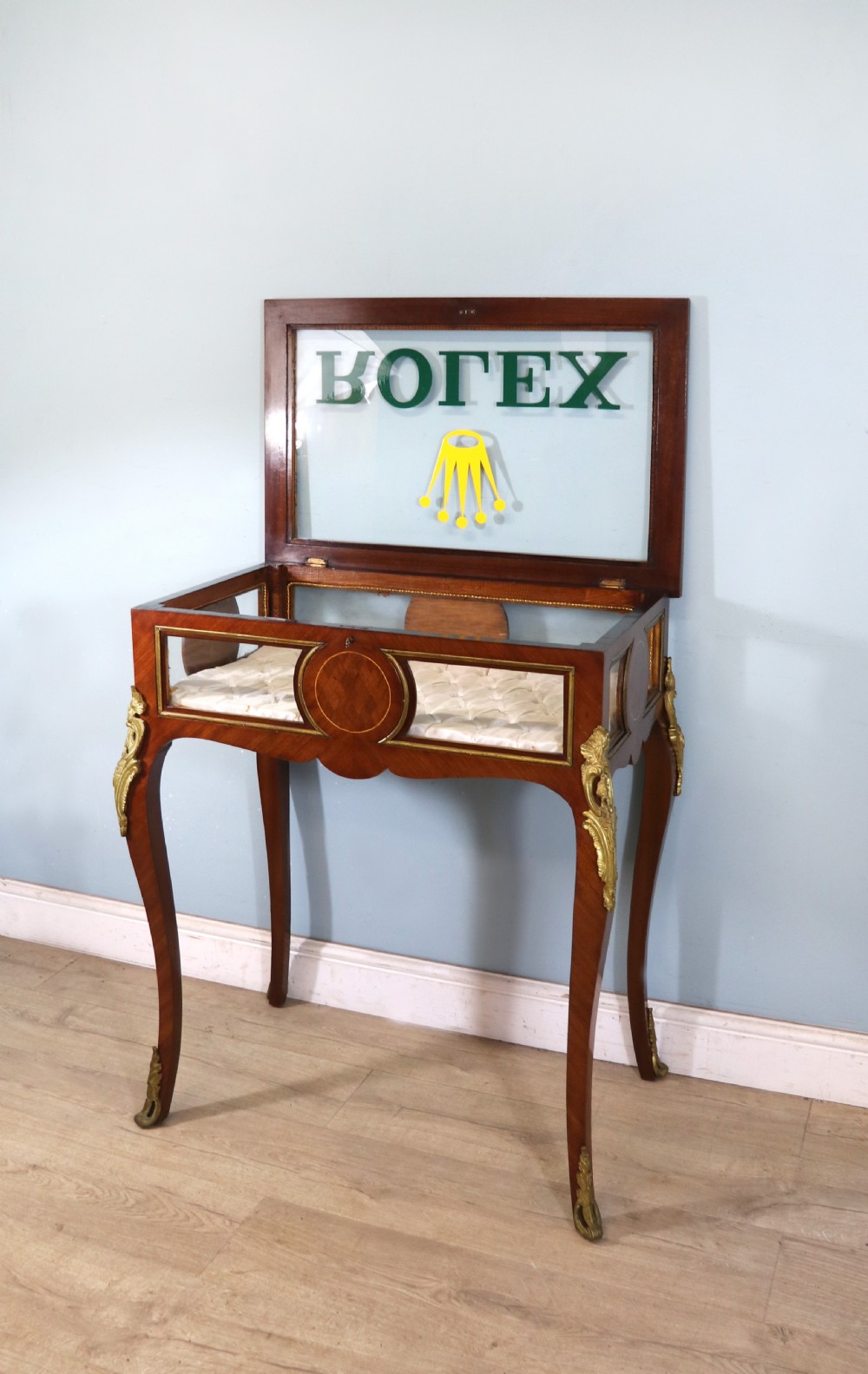 A mahogany and kingwood veneered bijouterie display table featuring glazed panels, cabriole legs with brass mounts, and a buttoned cream interior. View VII