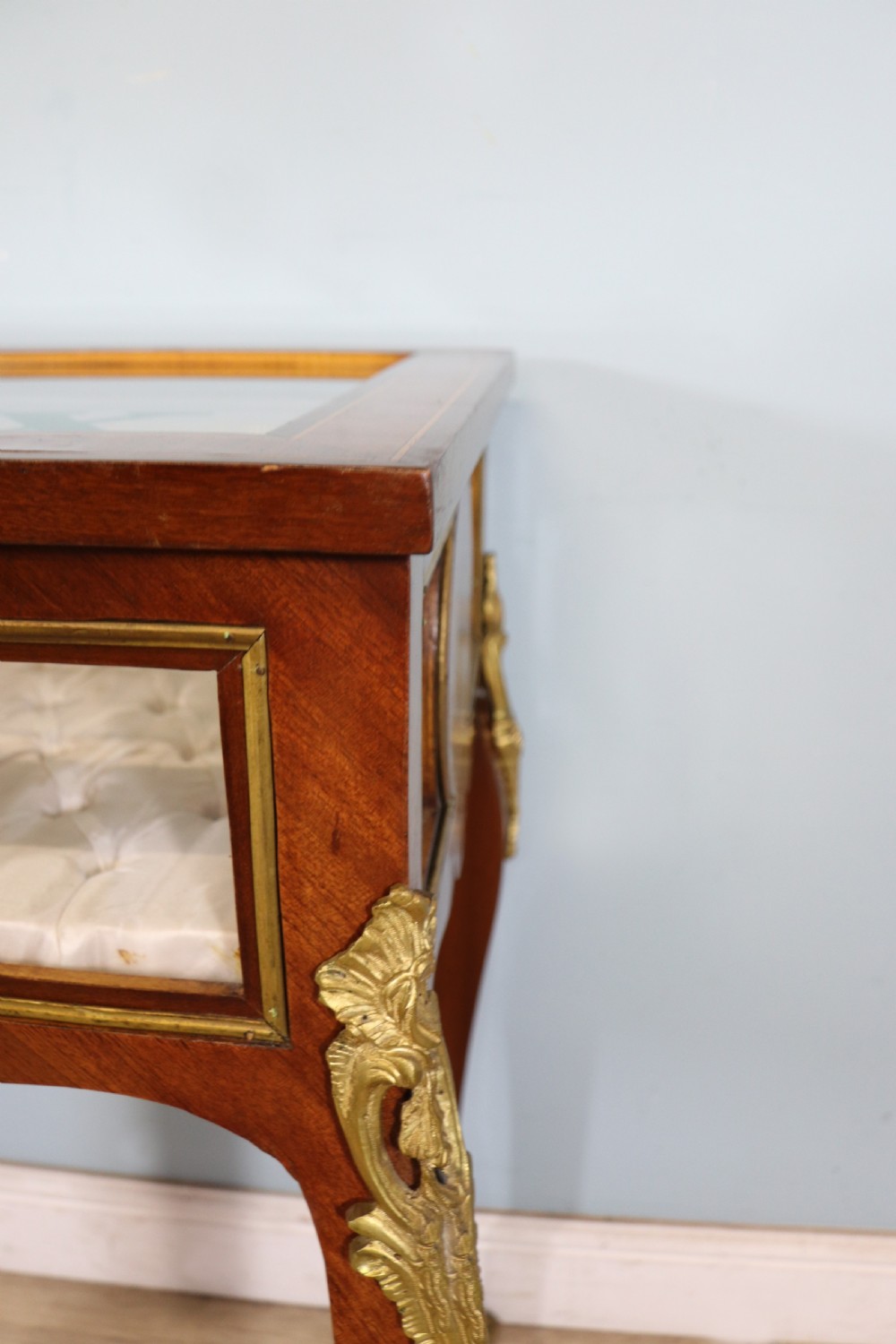 A mahogany and kingwood veneered bijouterie display table featuring glazed panels, cabriole legs with brass mounts, and a buttoned cream interior. View IX