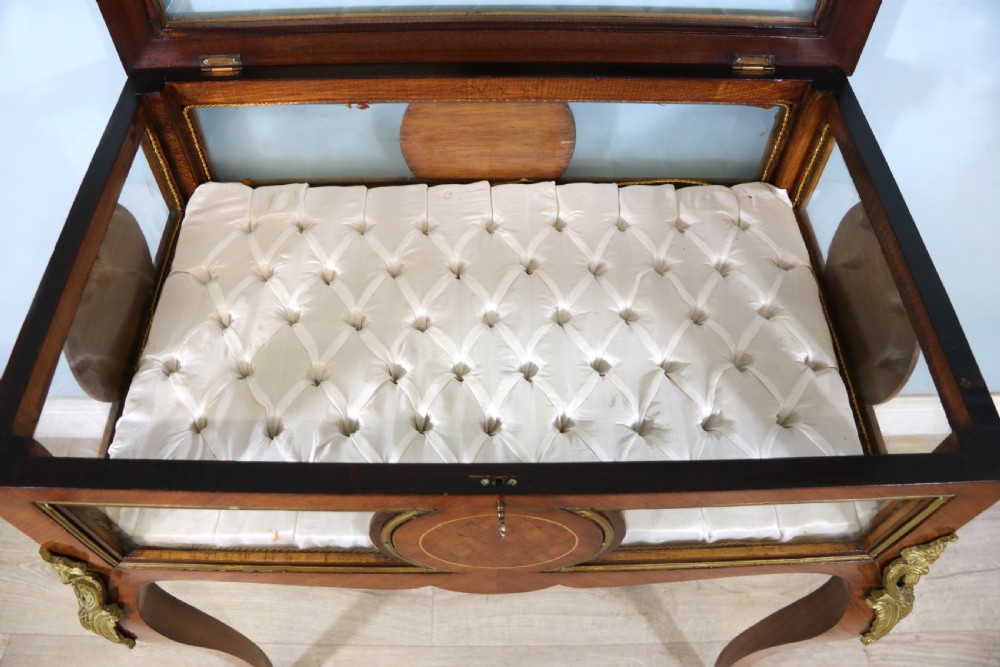 A mahogany and kingwood veneered bijouterie display table featuring glazed panels, cabriole legs with brass mounts, and a buttoned cream interior. View XI