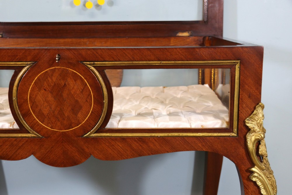 A mahogany and kingwood veneered bijouterie display table featuring glazed panels, cabriole legs with brass mounts, and a buttoned cream interior. View XXI