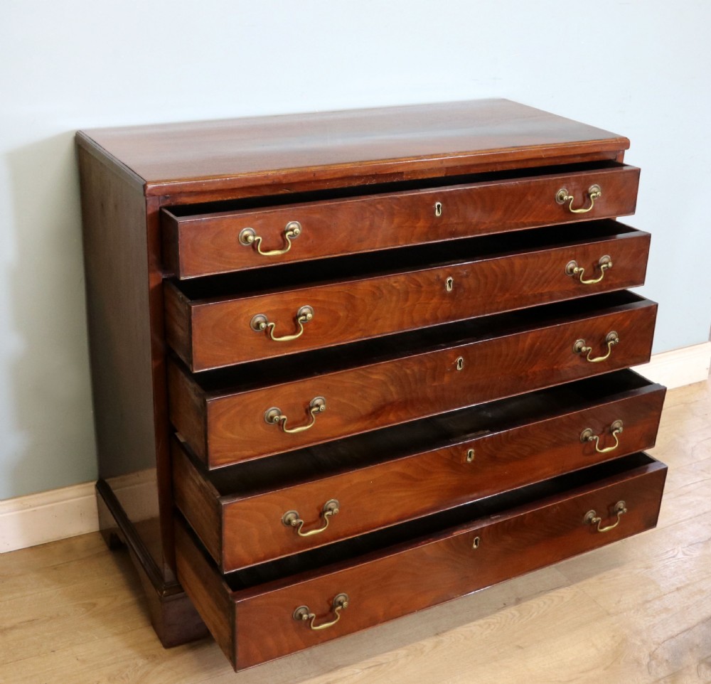A 19th-century mahogany chest of drawers featuring five graduated drawers with brass swan-neck handles and bracket feet. View V