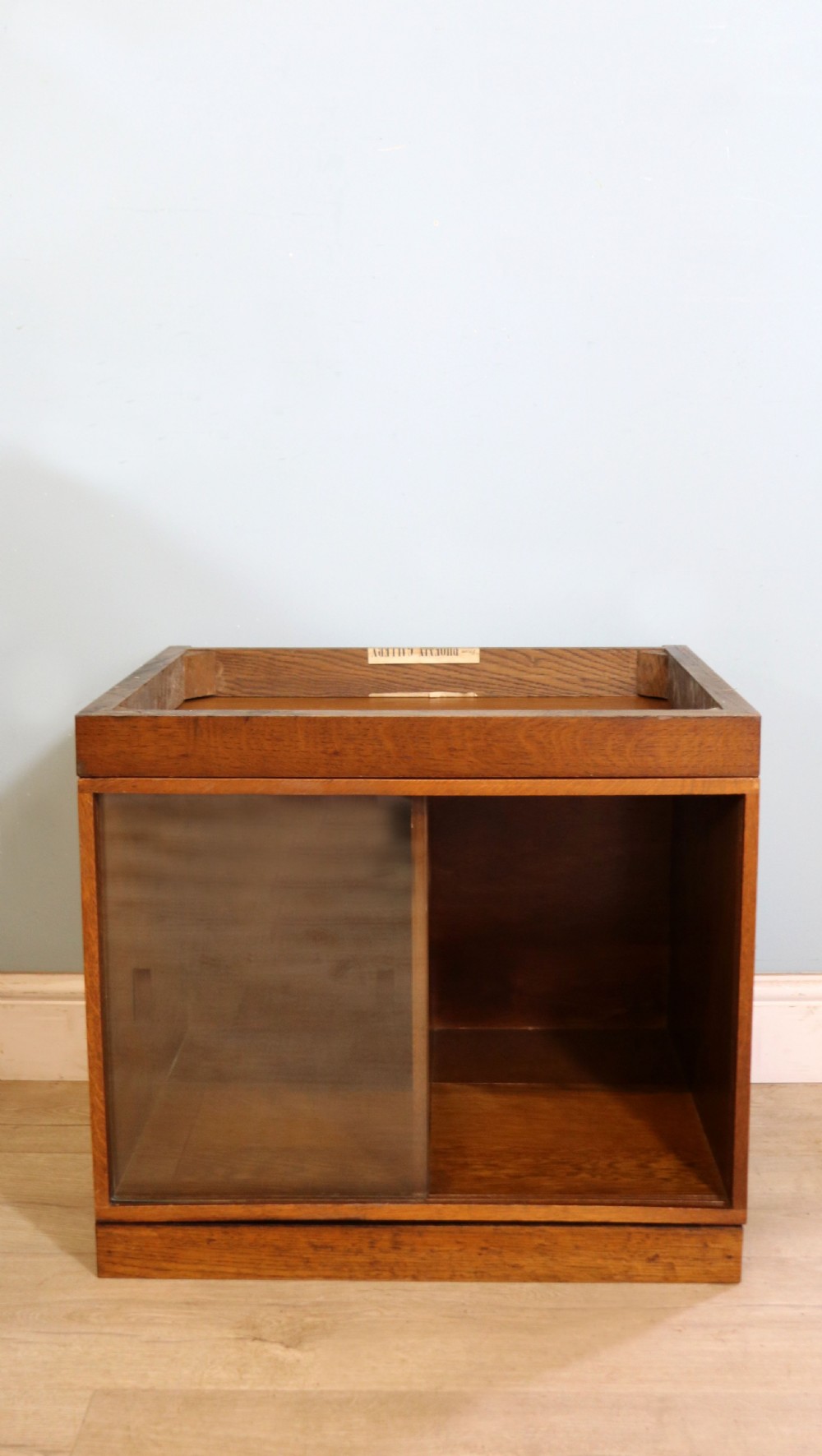 A three-tier mid-century oak sectional bookcase featuring sliding glass doors and a central section with a solid wood panel. View XII
