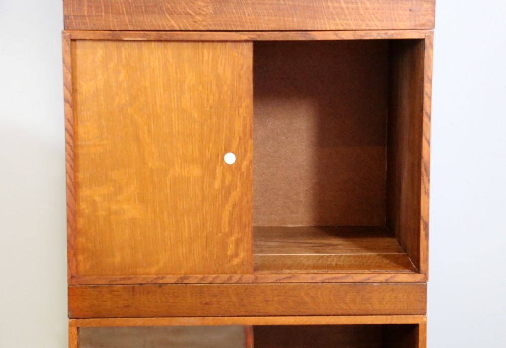 A three-tier mid-century oak sectional bookcase featuring sliding glass doors and a central section with a solid wood panel. View XXII
