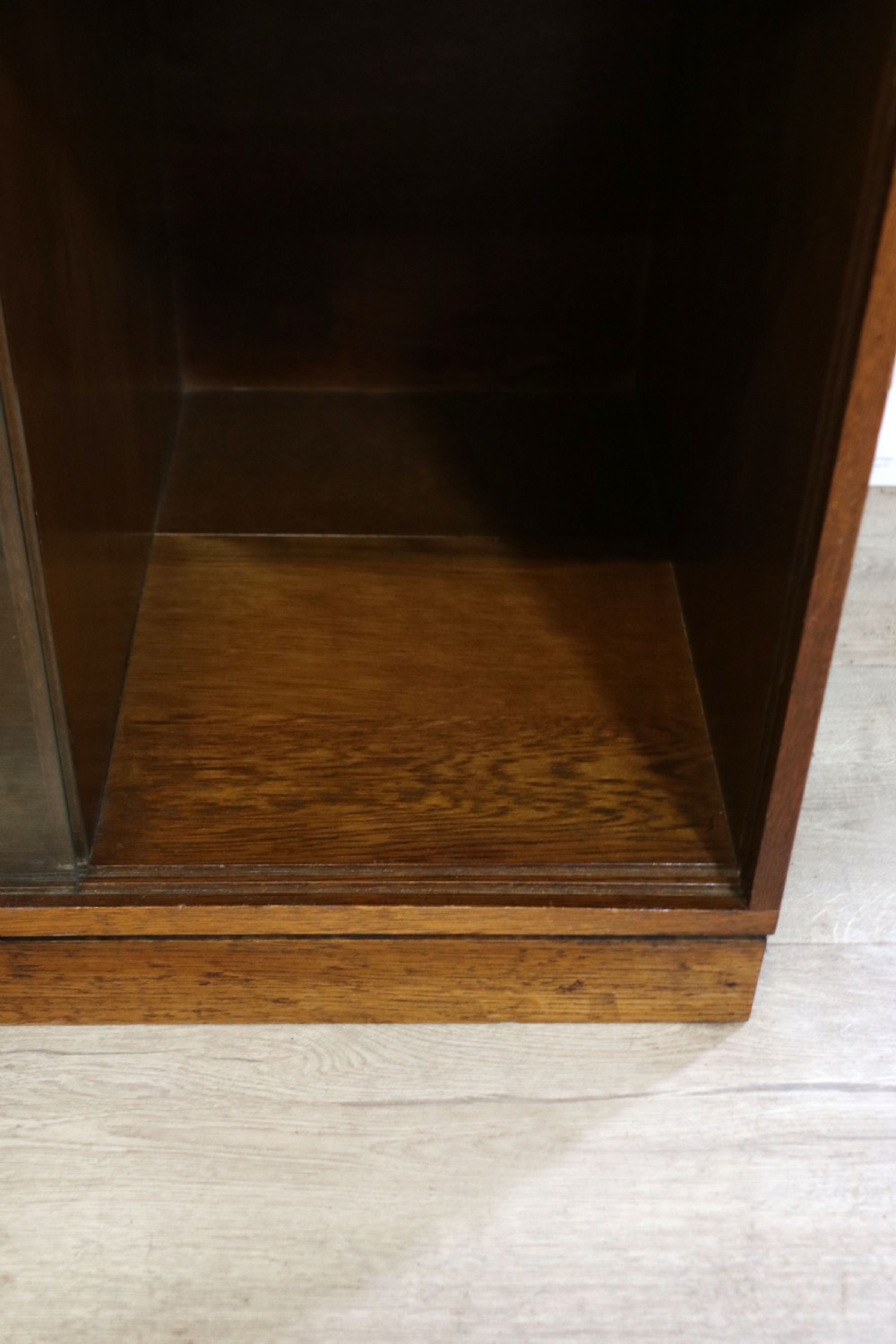 A three-tier mid-century oak sectional bookcase featuring sliding glass doors and a central section with a solid wood panel. View XXV