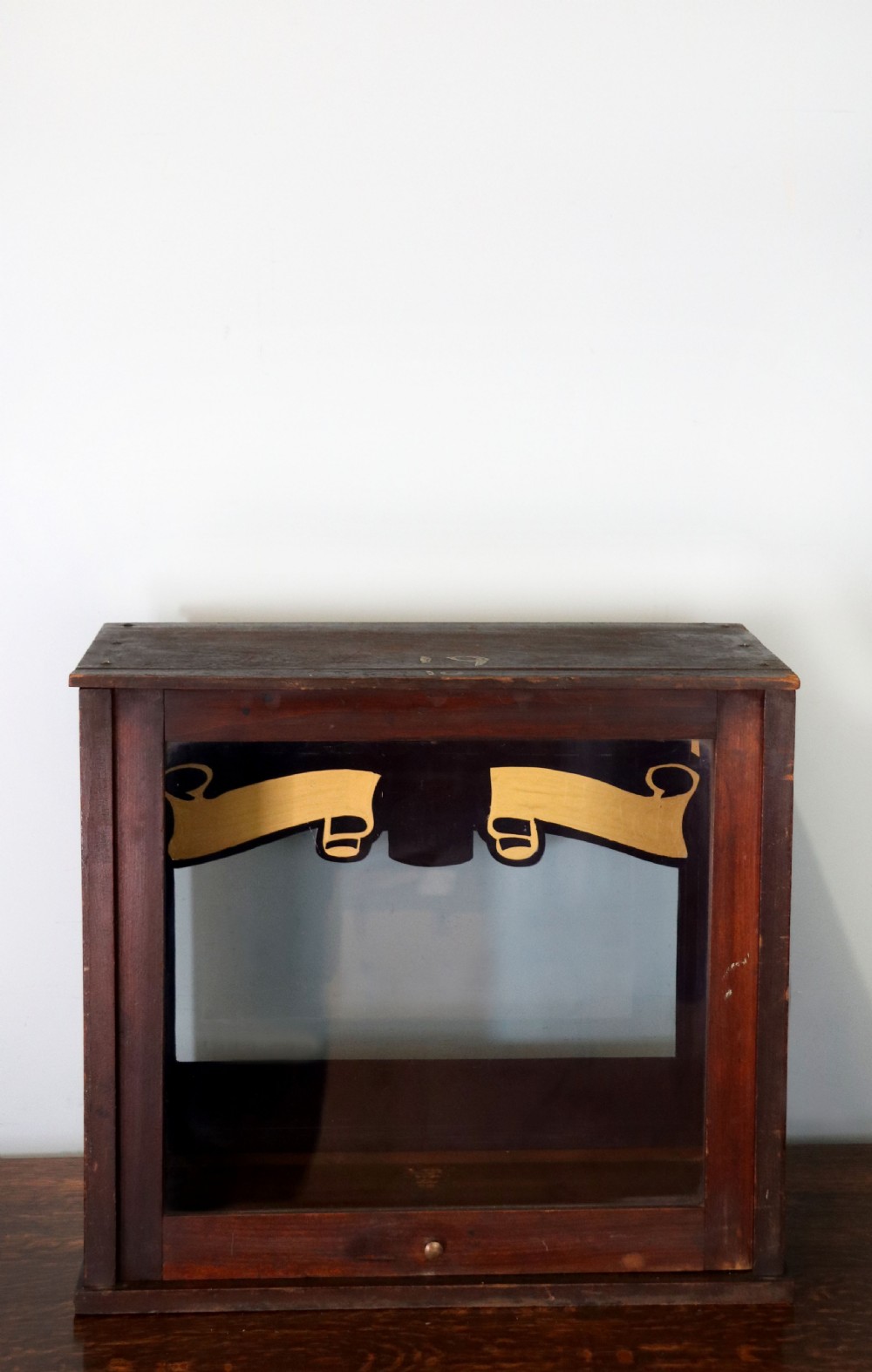 A dark hardwood rectangular shop display cabinet featuring gold lettering on the front glass pane reading Cadburys Dairy Milk Chocolate. View IV