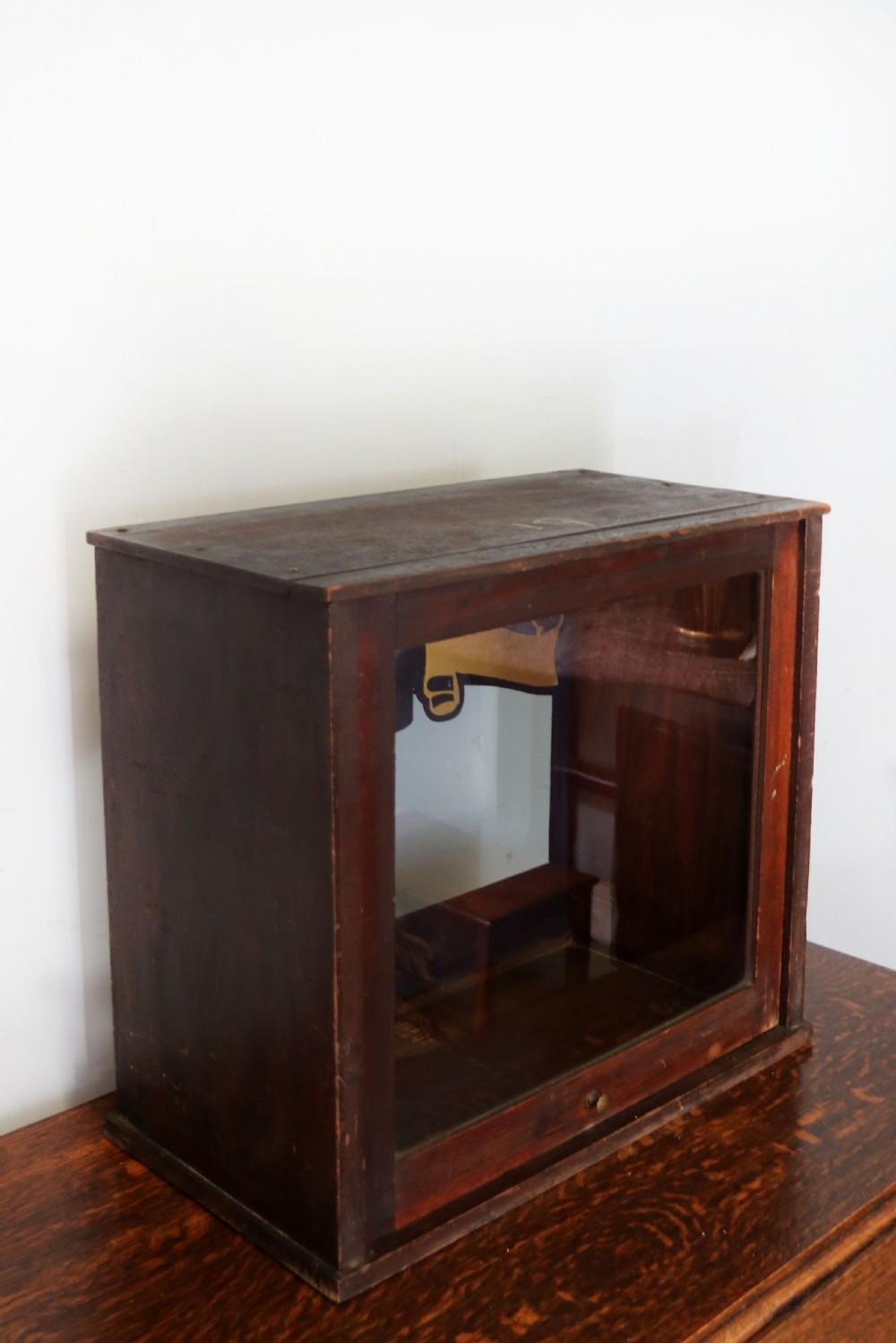 A dark hardwood rectangular shop display cabinet featuring gold lettering on the front glass pane reading Cadburys Dairy Milk Chocolate. View V