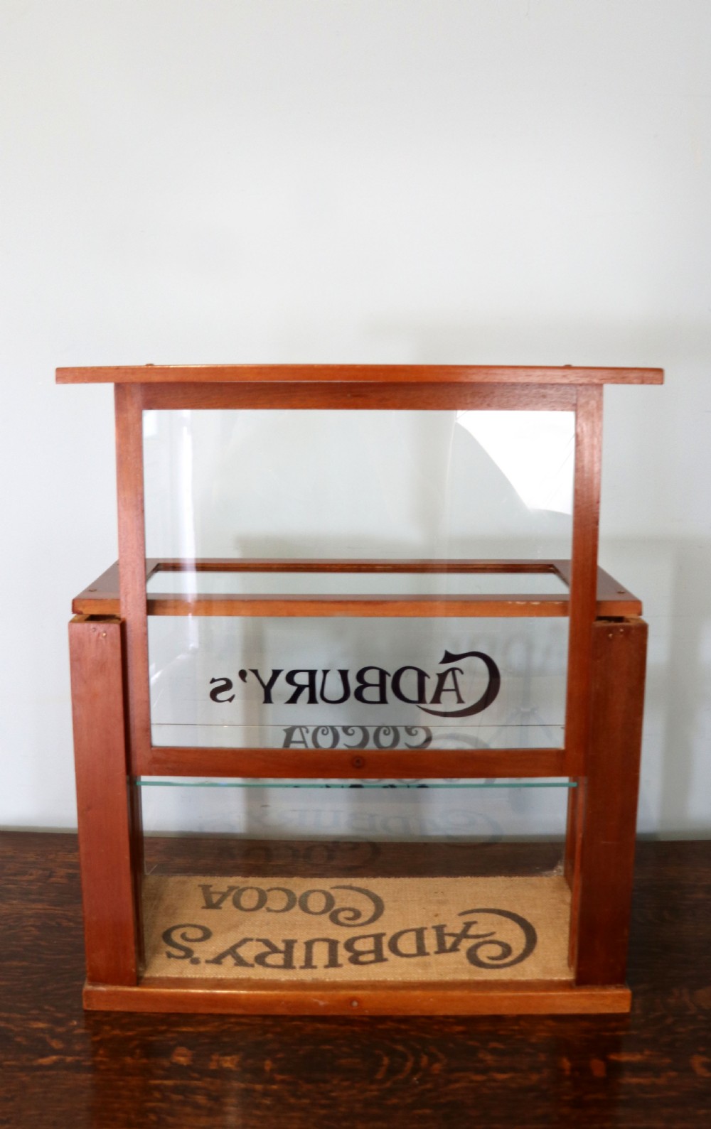 A glazed hardwood countertop display cabinet featuring Cadburys Cocoa typography printed on the front glass pane and inner base. View IV