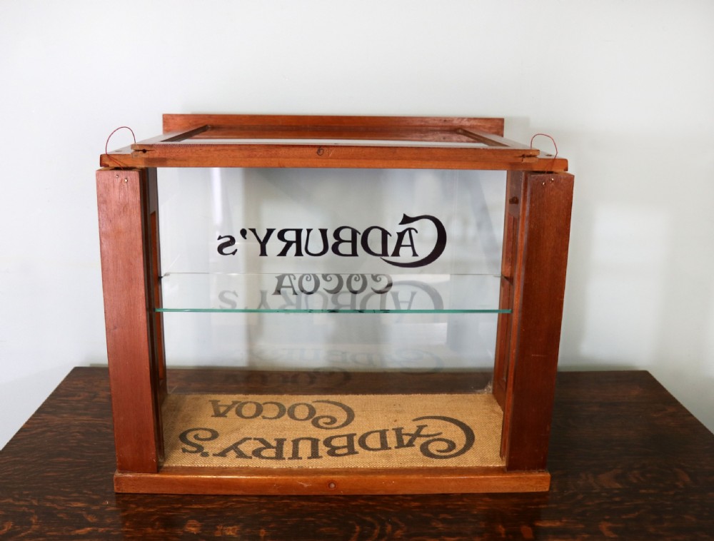 A glazed hardwood countertop display cabinet featuring Cadburys Cocoa typography printed on the front glass pane and inner base. View VI
