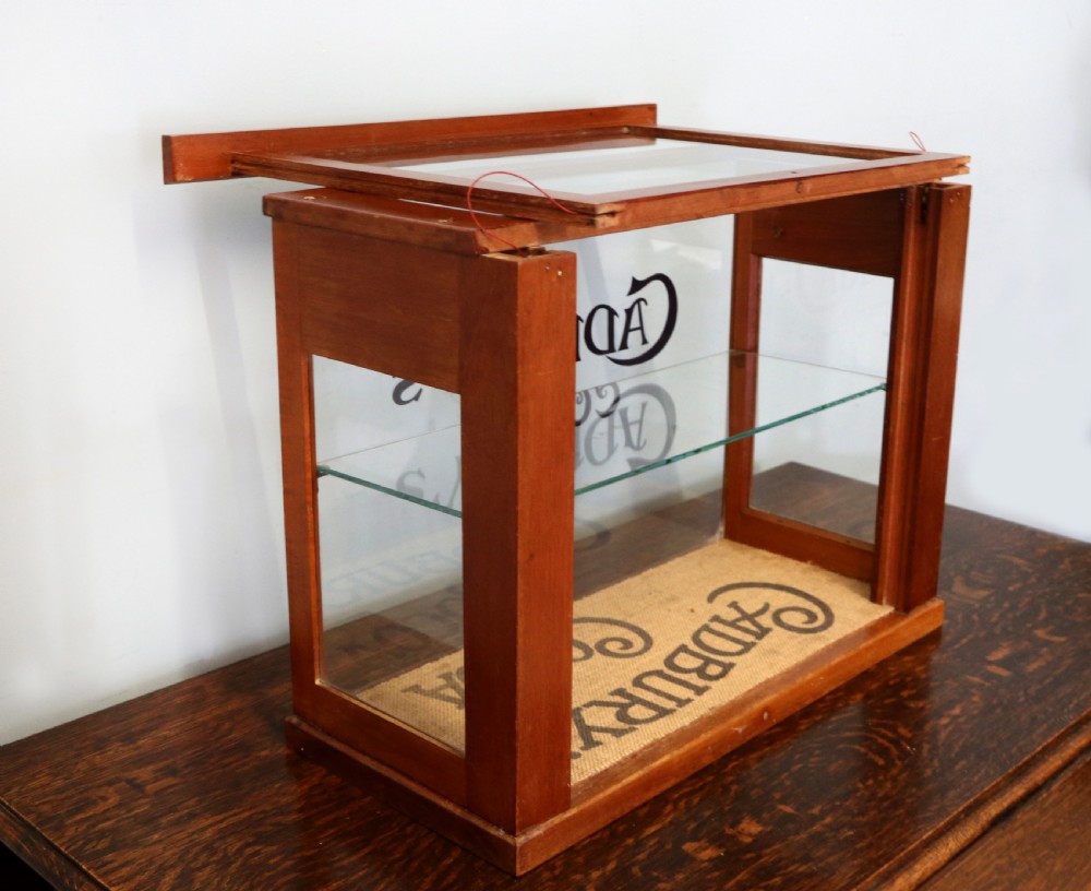 A glazed hardwood countertop display cabinet featuring Cadburys Cocoa typography printed on the front glass pane and inner base. View VIII