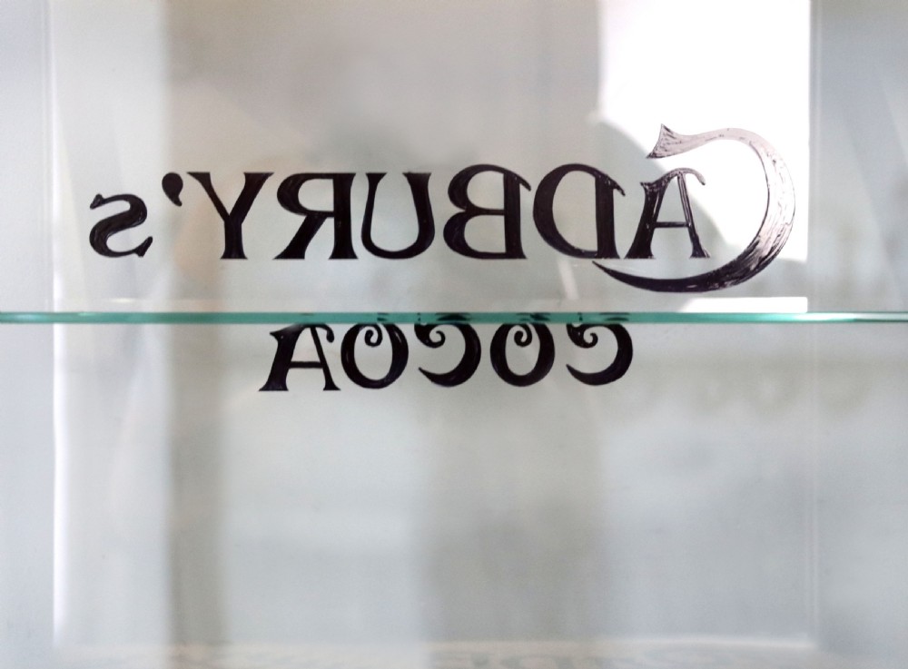A glazed hardwood countertop display cabinet featuring Cadburys Cocoa typography printed on the front glass pane and inner base. View XIII