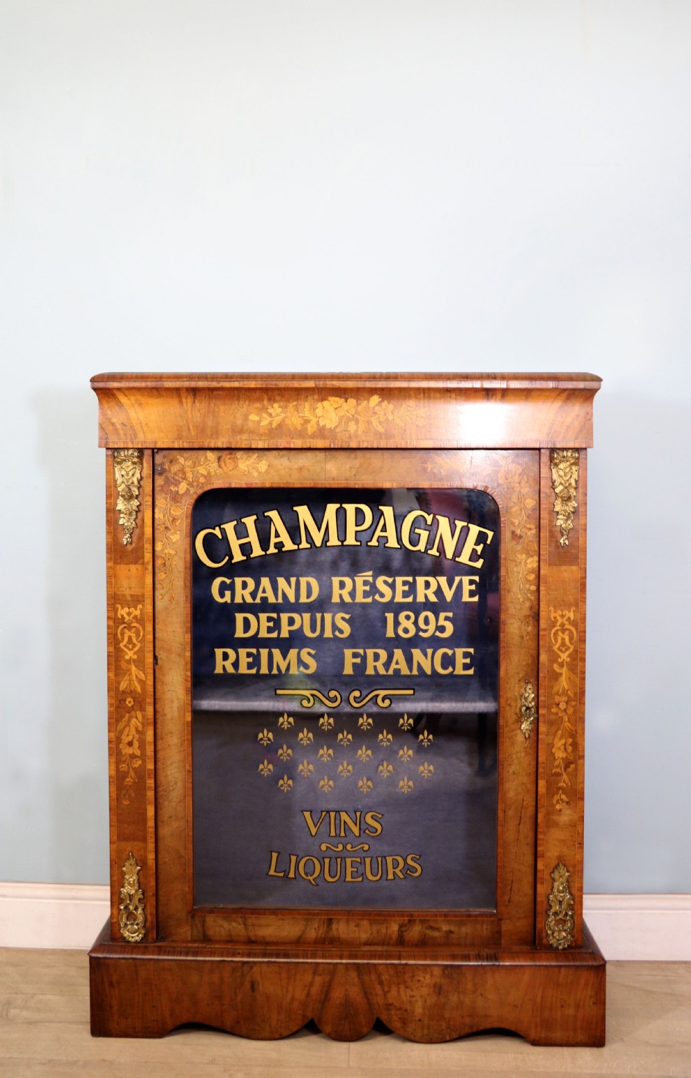 A lovely Victorian walnut and floral inlaid pier cabinet, later sign written in French with Champagne advertising.