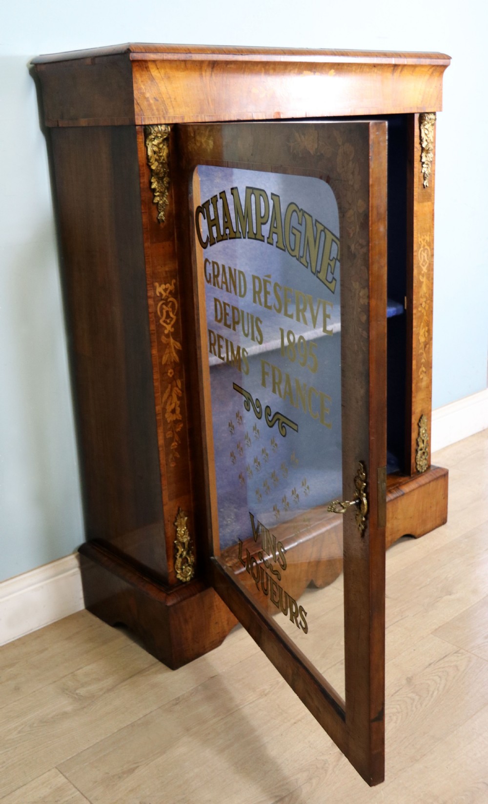 A lovely Victorian walnut and floral inlaid pier cabinet, later sign written in French with Champagne advertising. View V