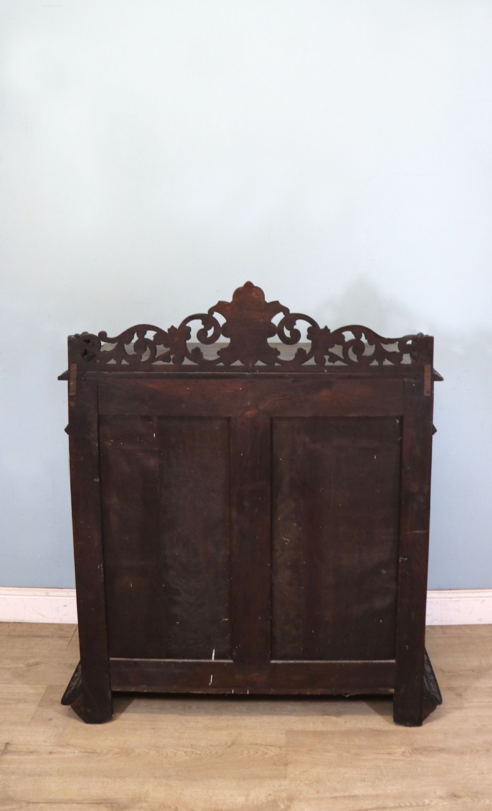 A dark carved oak side cabinet with a single glazed door displaying painted brewery signwriting and an ornate carved gallery back. View VII