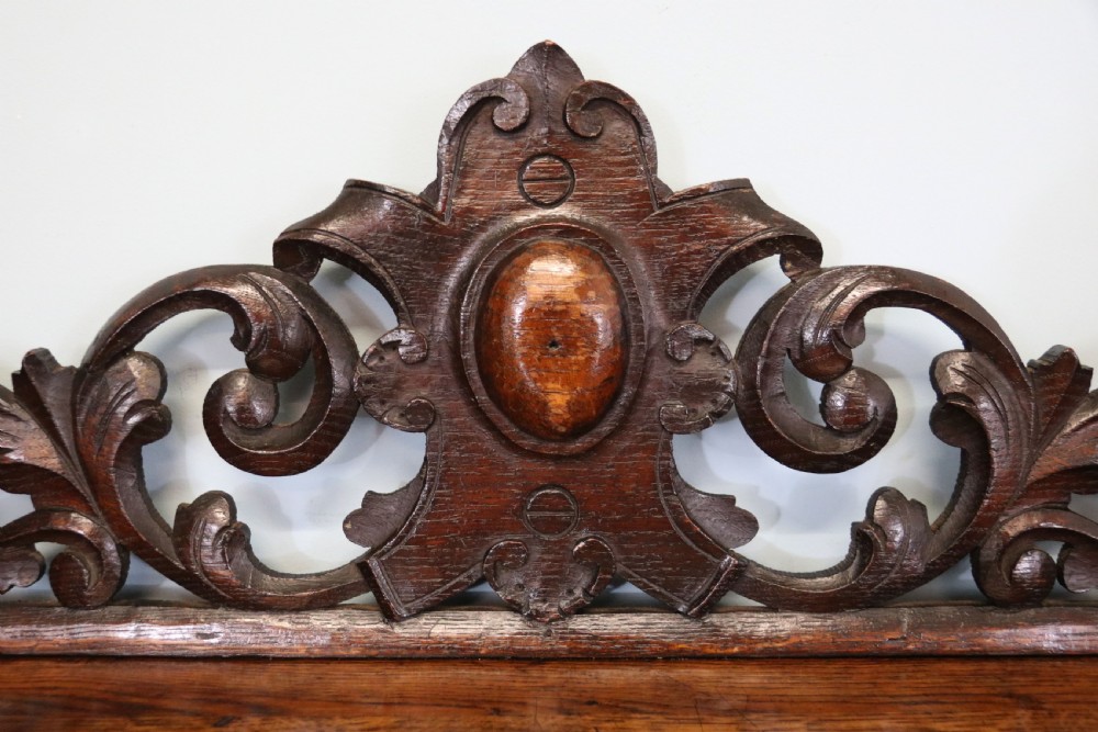 A dark carved oak side cabinet with a single glazed door displaying painted brewery signwriting and an ornate carved gallery back. View X