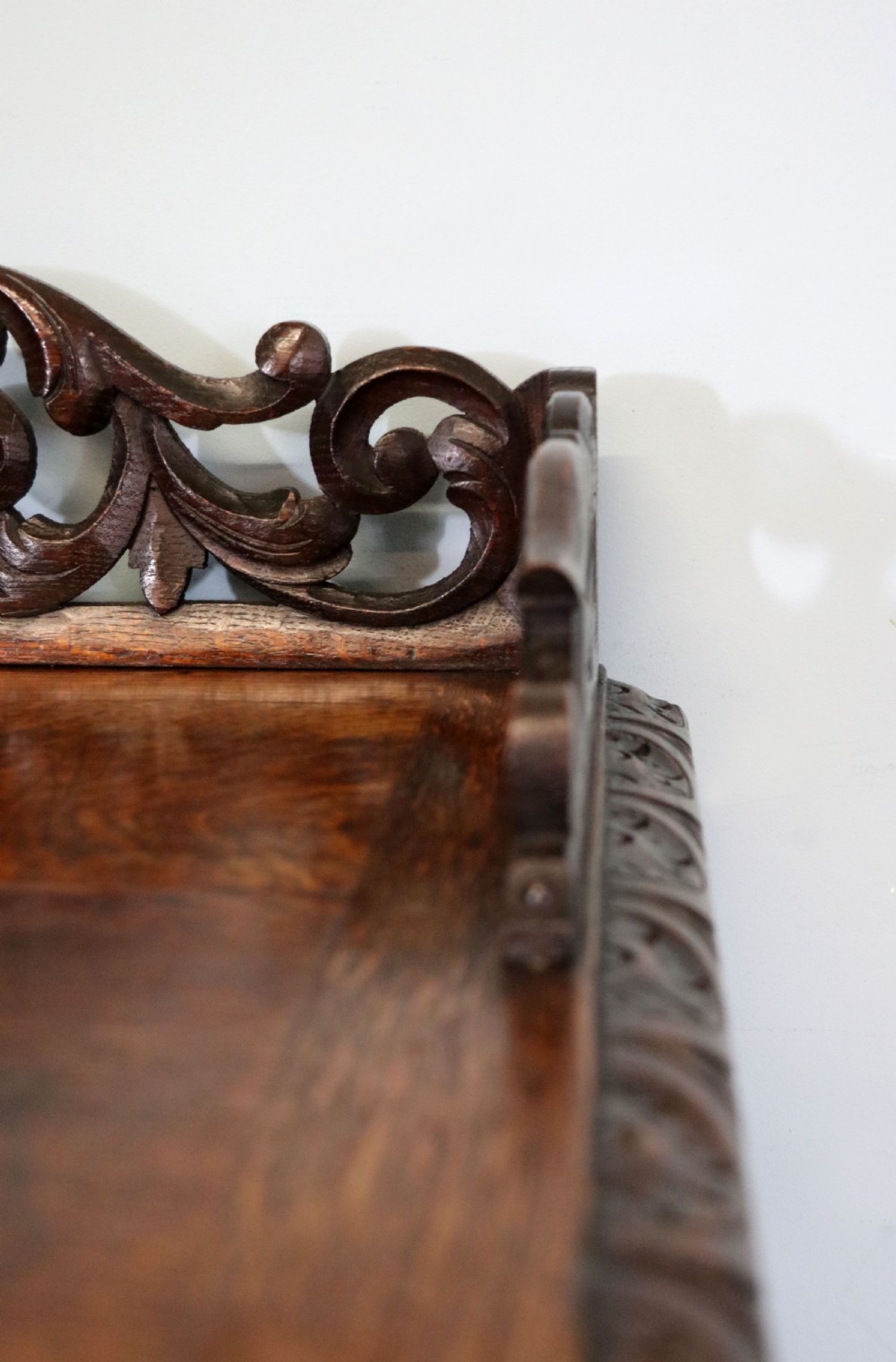 A dark carved oak side cabinet with a single glazed door displaying painted brewery signwriting and an ornate carved gallery back. View XII