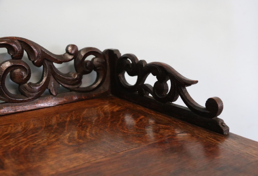 A dark carved oak side cabinet with a single glazed door displaying painted brewery signwriting and an ornate carved gallery back. View XIII