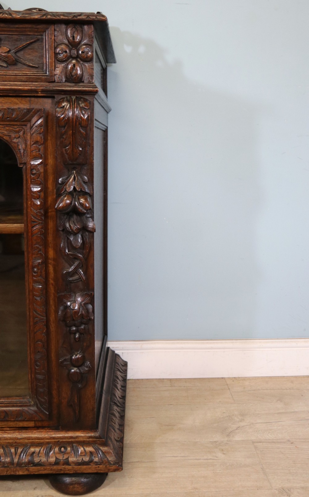 A dark carved oak side cabinet with a single glazed door displaying painted brewery signwriting and an ornate carved gallery back. View XVI