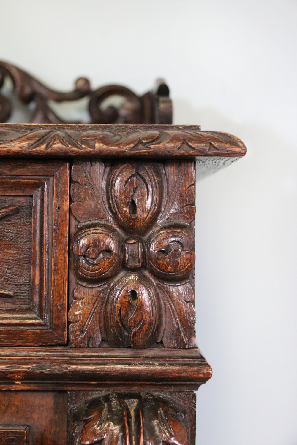 A dark carved oak side cabinet with a single glazed door displaying painted brewery signwriting and an ornate carved gallery back. View XVII