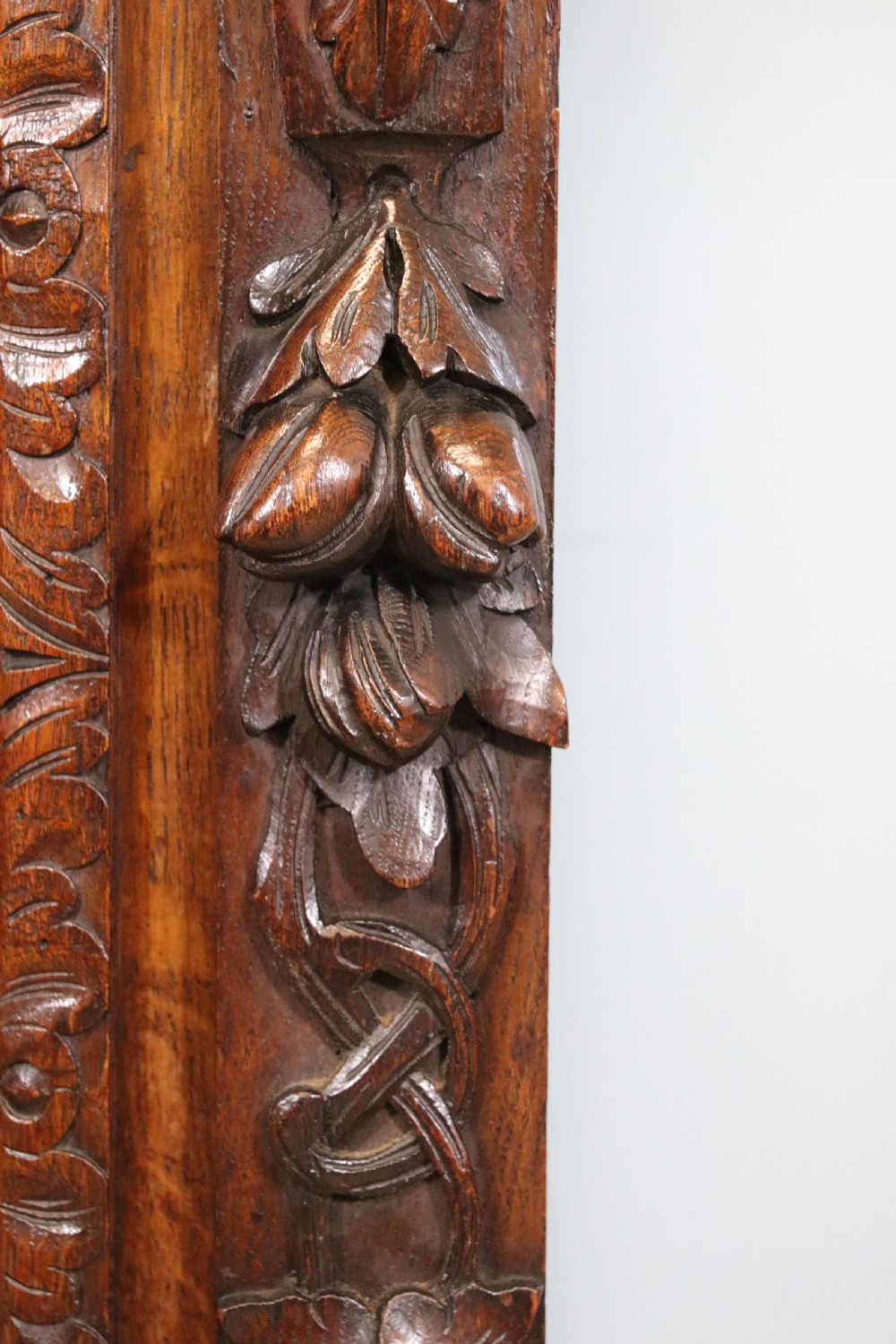 A dark carved oak side cabinet with a single glazed door displaying painted brewery signwriting and an ornate carved gallery back. View XIX