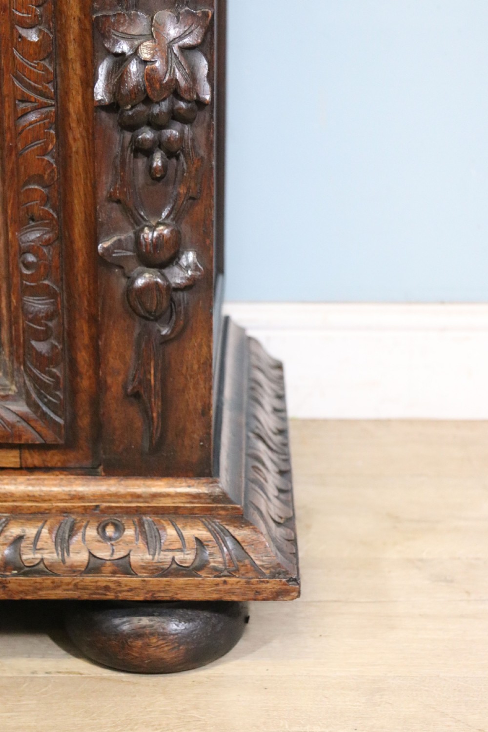 A dark carved oak side cabinet with a single glazed door displaying painted brewery signwriting and an ornate carved gallery back. View XXI