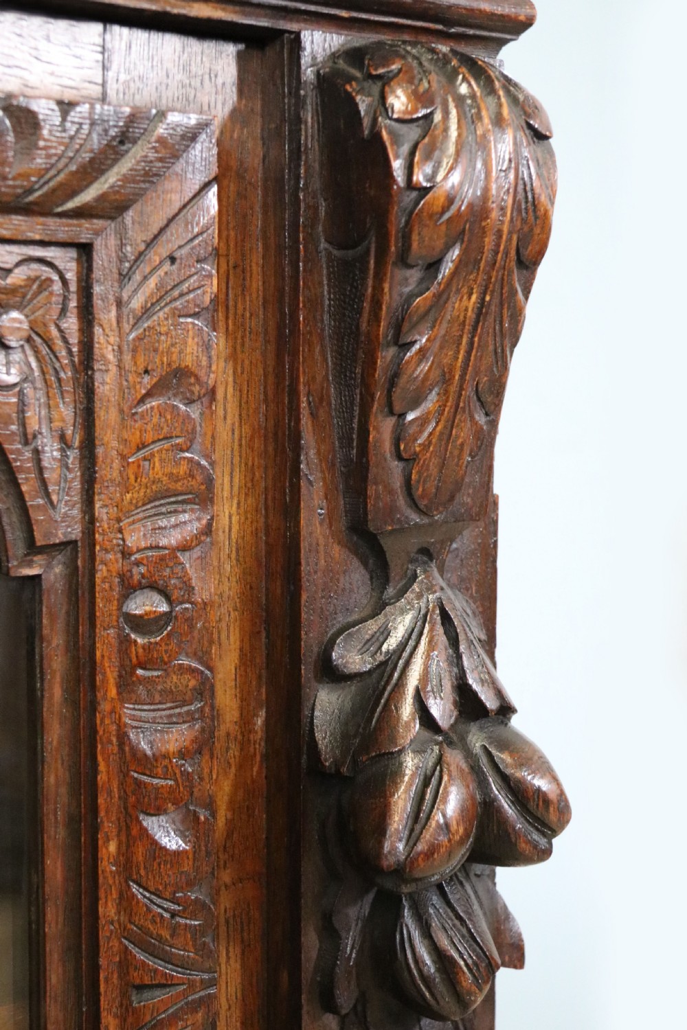A dark carved oak side cabinet with a single glazed door displaying painted brewery signwriting and an ornate carved gallery back. View XXII