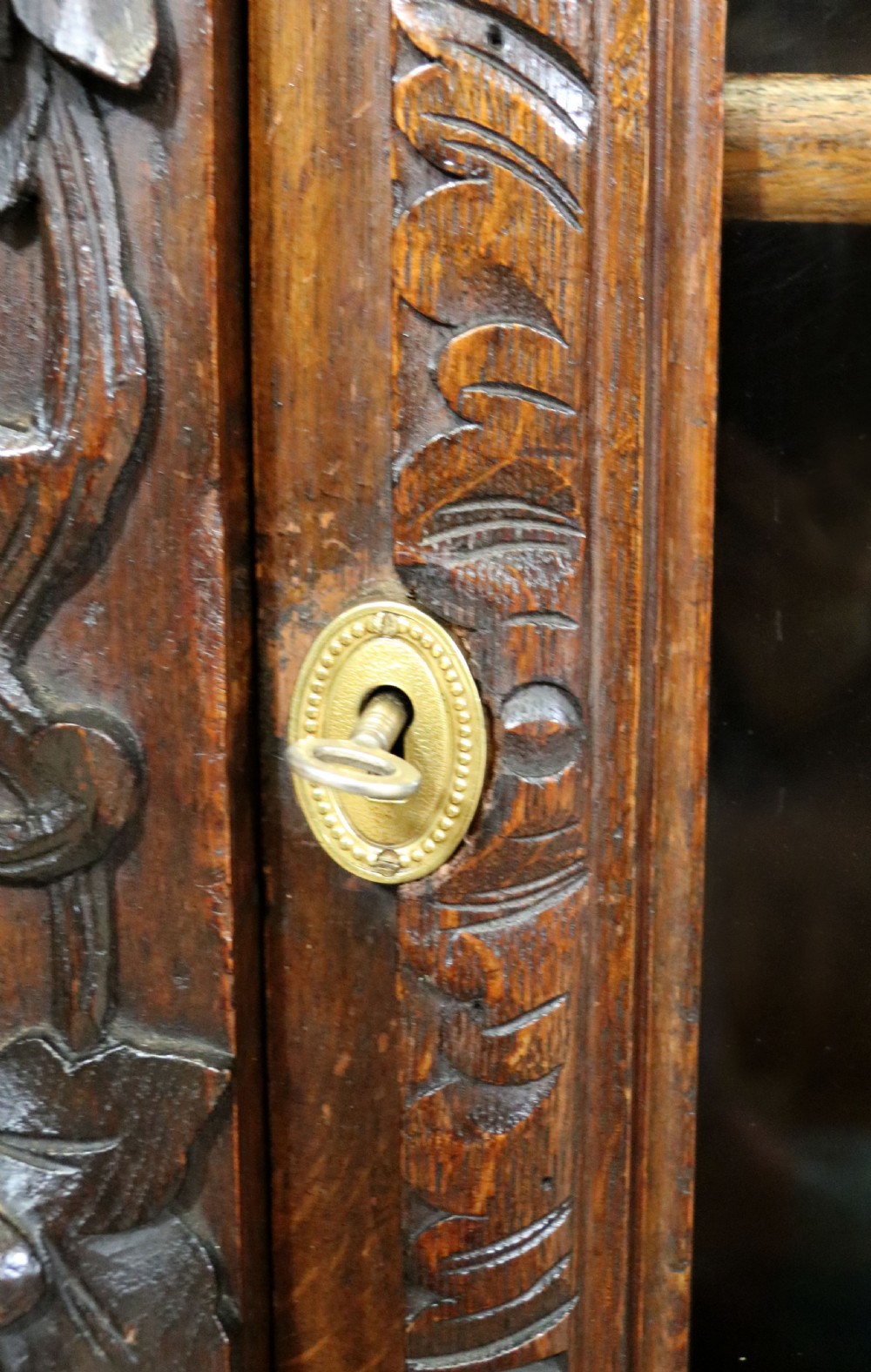 A dark carved oak side cabinet with a single glazed door displaying painted brewery signwriting and an ornate carved gallery back. View XXVIII
