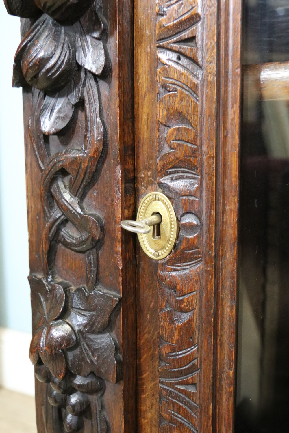 A dark carved oak side cabinet with a single glazed door displaying painted brewery signwriting and an ornate carved gallery back. View XXIX
