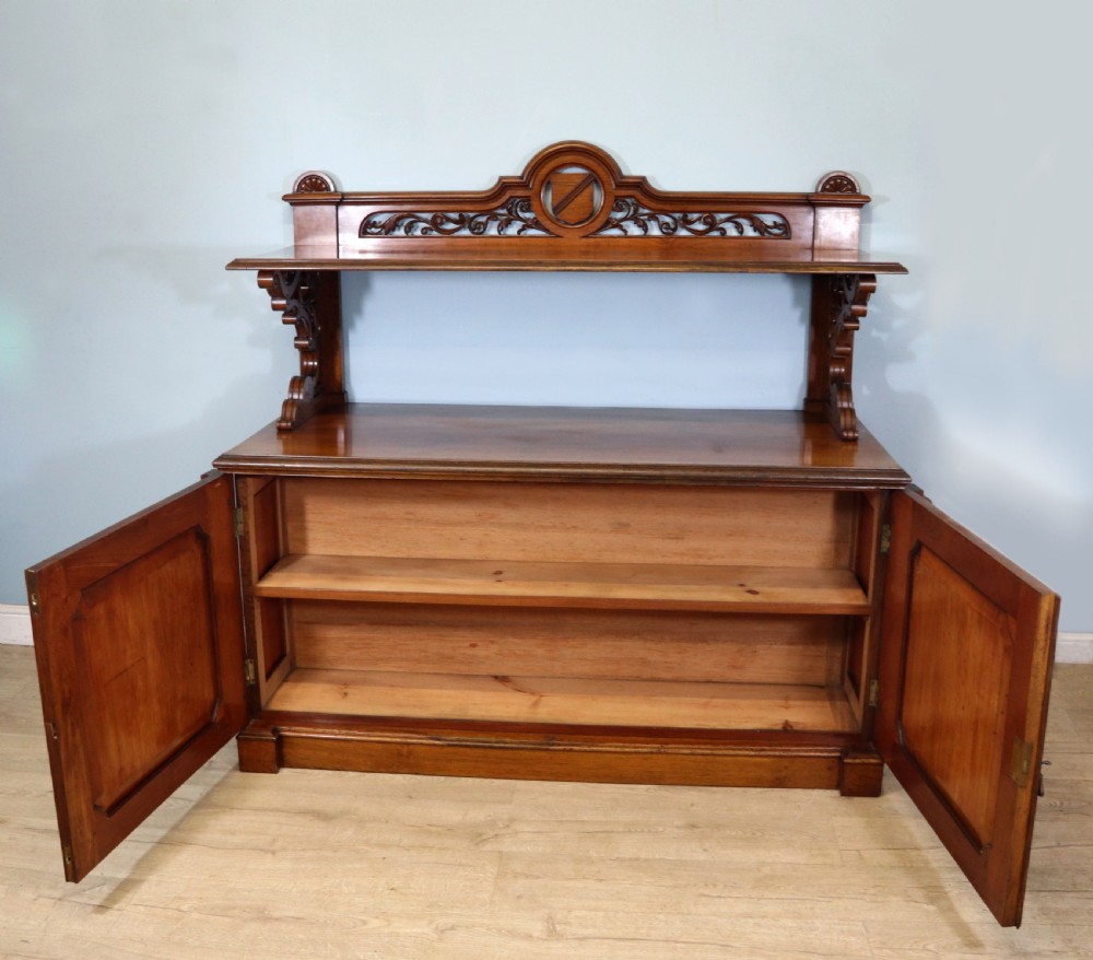 A Victorian pollard oak sideboard featuring a carved upper display shelf, fretwork cresting, and two fielded panel doors with decorative wood grain. View II
