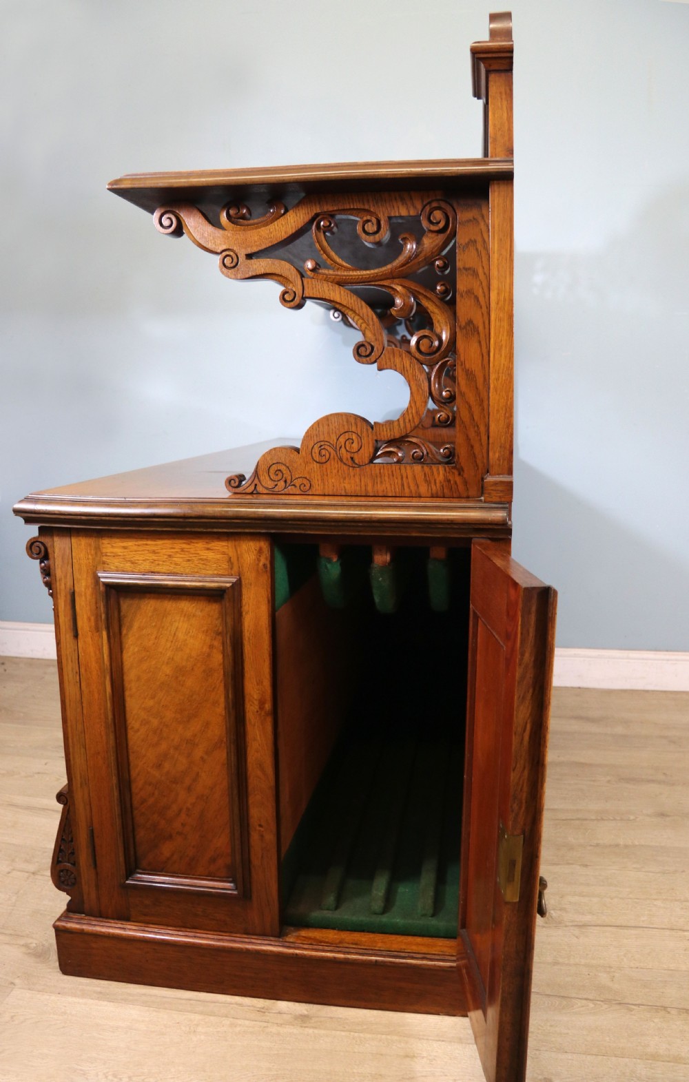 A Victorian pollard oak sideboard featuring a carved upper display shelf, fretwork cresting, and two fielded panel doors with decorative wood grain. View V