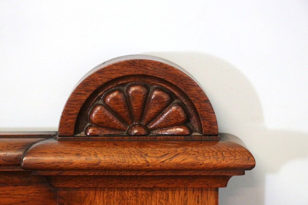 A Victorian pollard oak sideboard featuring a carved upper display shelf, fretwork cresting, and two fielded panel doors with decorative wood grain. View XII